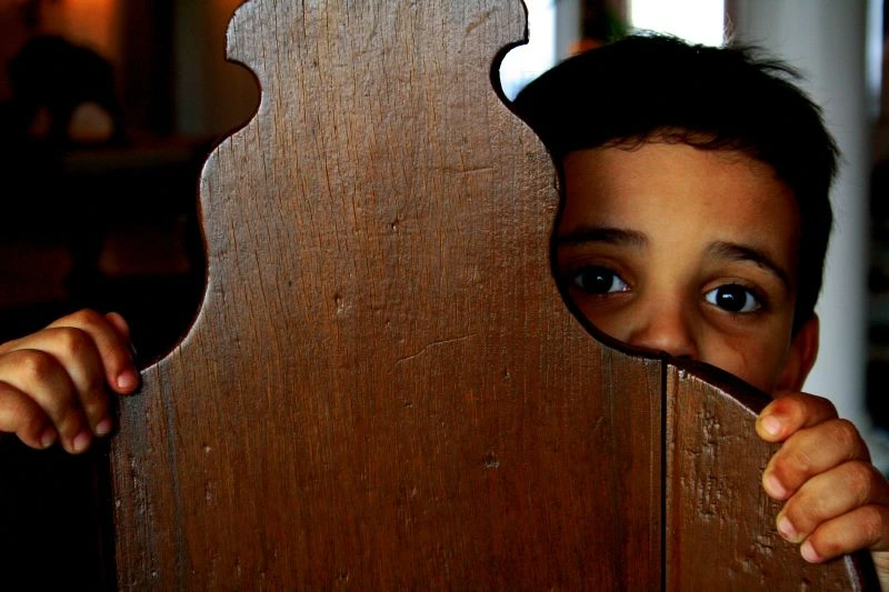 Fear of Failure, A scared child hiding behind a chair, StudySmarter