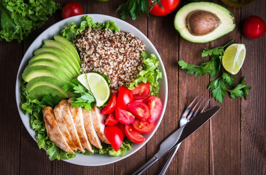 A chicken, quinoa, avocado and tomato salad nicely presented in a bowl on a table. Vaia Magazine